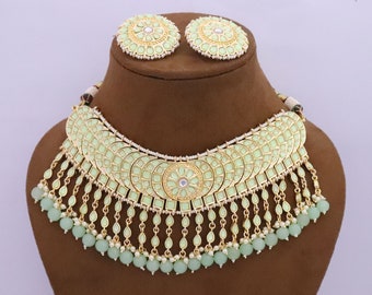 May include: A mint green and gold-toned necklace and earring set. The necklace features a series of connected, fan-shaped pendants with dangling teardrop charms and beaded accents. The matching earrings are round with a similar design.