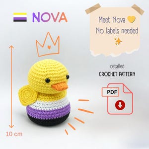 May include: A crocheted duck toy, approximately 4 inches tall, in yellow, orange, purple, white, and black. The duck has a non-binary flag design on its body. Text includes "NOVA", "Meet Nova, No labels needed", and "detailed CROCHET PATTERN PDF".