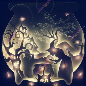 May include: A white silhouette of a witch stirring a cauldron with a black cat sitting in front of it. The scene is set against a backdrop of a spooky forest and a haunted house. The image is illuminated with warm white lights.