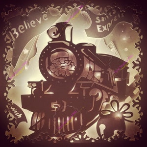 Peut inclure: Une silhouette noire d'un train avec les mots "Santa Express" et "Believe" en haut et "Wish" en bas. Le train est éclairé par derrière, créant un effet lumineux.