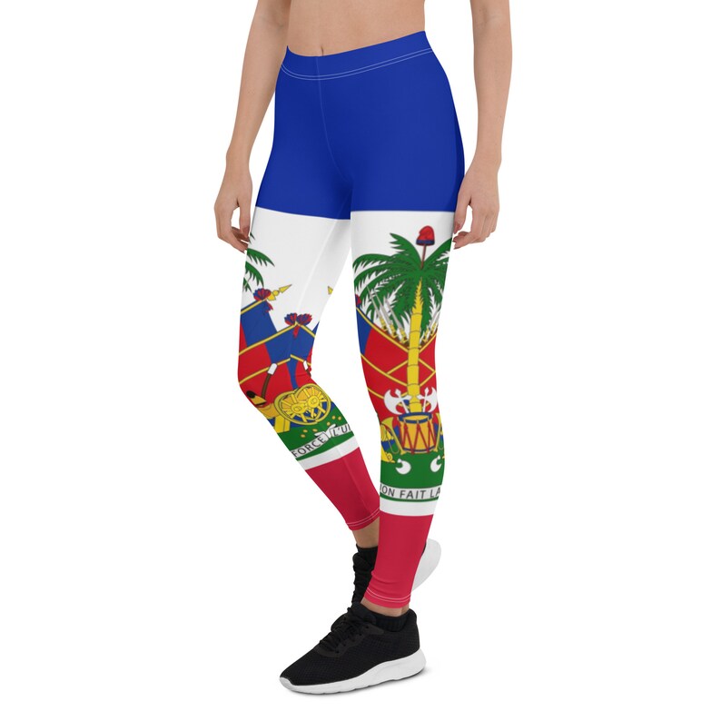Może przedstawiać: Legginsy w kolorze niebieskim, czerwonym i zielonym z nadrukiem flagi Haiti. Legginsy mają biały pasek w środku z nadrukiem herbu Haiti. Na legginsach widnieje napis "L'UNION FAIT LA FORCE".