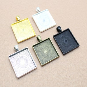 May include: Five square pendant trays in different finishes: gold, silver, antique brass, black, and white. Each tray has a decorative pattern.