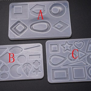 May include: Three clear silicone molds for making resin earrings. The molds are labeled A, B, and C. Mold A has shapes like circles, ovals, and squares. Mold B has shapes like hearts, leaves, and stars. Mold C has shapes like triangles, stars, and teardrops.