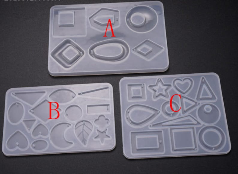 May include: Three clear silicone molds for making resin earrings. The molds are labeled A, B, and C. Mold A has shapes like circles, ovals, and squares. Mold B has shapes like hearts, leaves, and stars. Mold C has shapes like triangles, stars, and teardrops.