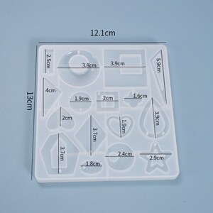 May include: A clear silicone mold with 13 different shapes for making jewelry. The mold measures 12.1 cm by 13 cm and includes shapes like a heart, star, circle, and square.