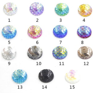 May include: Assortment of 15 round iridescent resin cabochons with a fish scale pattern. The cabochons are in various colors, including blue, purple, green, gold, silver, and black.