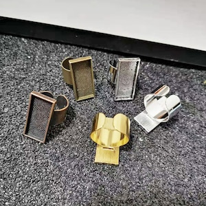 May include: Four adjustable ring blanks with a textured surface. The blanks are in gold, silver, and bronze.