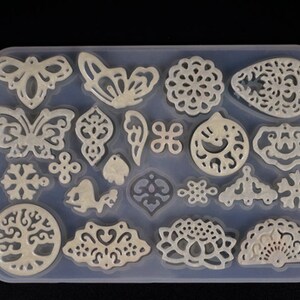 May include: A clear silicone mold with 20 different designs for making jewelry. The designs include butterflies, snowflakes, flowers, and a tree of life.