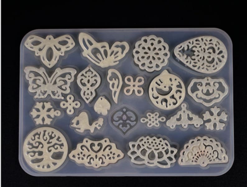 May include: A clear silicone mold with 20 different designs for making jewelry. The designs include butterflies, snowflakes, flowers, and a tree of life.
