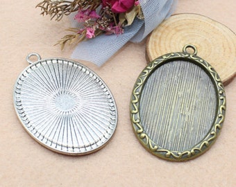Puede incluir: Dos bandejas ovaladas de metal para colgantes, una plateada y otra bronce. Ambas bandejas tienen un borde elevado y una superficie texturizada. La bandeja plateada tiene un diseño de rayos de sol, mientras que la bandeja de bronce tiene un borde decorativo.