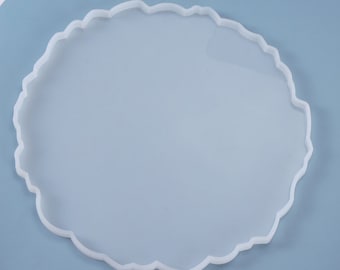 May include: White silicone mold with a round, irregular edge. The mold is designed for creating resin coasters or trays.
