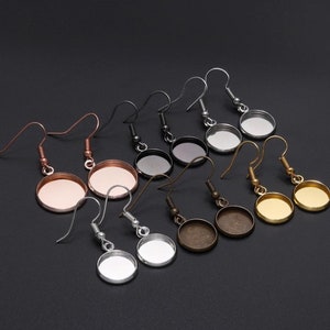 May include: Assortment of eight pairs of silver, gold, bronze, and black earring blanks with round glass cabochon settings.