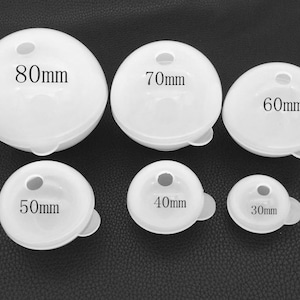Op de afbeelding: Set van zes ronde witte kunststof mallen voor het maken van bolvormige harsambachten. De mallen zijn gelabeld met hun diameter in millimeters: 80 mm, 70 mm, 60 mm, 50 mm, 40 mm en 30 mm.