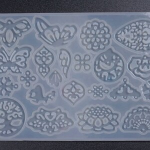 May include: A clear silicone mold with 18 different designs, including butterflies, snowflakes, flowers, and a tree of life. The mold is perfect for creating resin jewelry, ornaments, or other crafts.