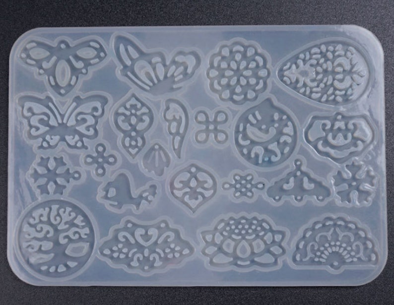 May include: A clear silicone mold with 18 different designs, including butterflies, snowflakes, flowers, and a tree of life. The mold is perfect for creating resin jewelry, ornaments, or other crafts.