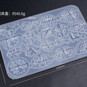May include: A clear silicone mold with 15 different shapes for resin casting. The mold is 10 cm by 14.4 cm and weighs 40.6 grams. The shapes include butterflies, leaves, and abstract designs.