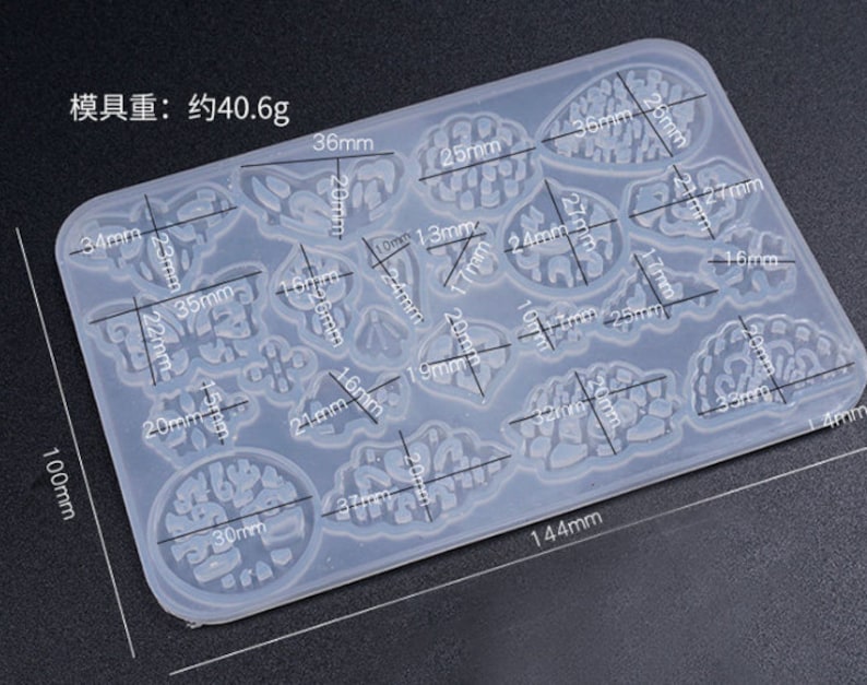 May include: A clear silicone mold with 15 different shapes for resin casting. The mold is 10 cm by 14.4 cm and weighs 40.6 grams. The shapes include butterflies, leaves, and abstract designs.