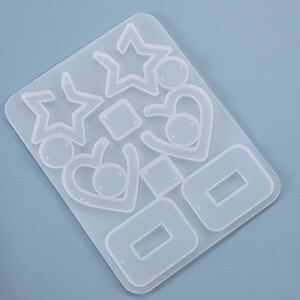 May include: Clear silicone mold for making earrings. The mold has multiple shapes including stars, hearts, and squares.