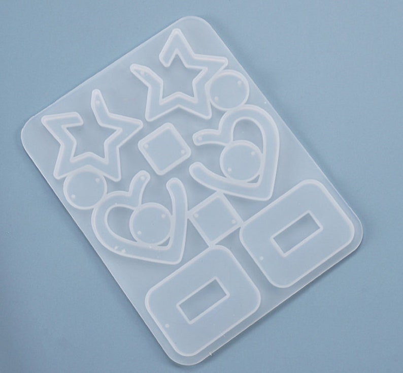 May include: Clear silicone mold for making earrings. The mold has multiple shapes including stars, hearts, and squares.