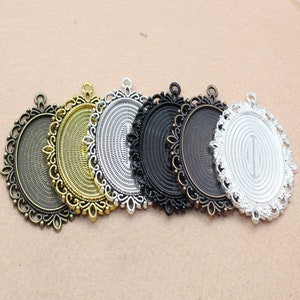May include: Six oval-shaped metal pendant trays with ornate edges. The trays are in various finishes, including silver, gold, and black.