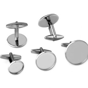Könnte beinhalten: Fünf silberne Manschettenknöpfe mit runden, leeren, weißen Zentren. Die Manschettenknöpfe haben ein schlichtes, klassisches Design.