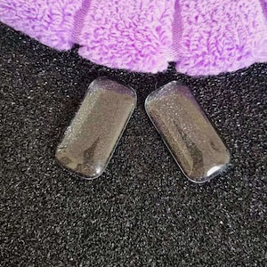 May include: Two clear, rectangular, glitter-filled containers with a black background.