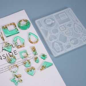 May include: A clear silicone mold with various shapes for making earrings. The mold is filled with green and gold resin, showing the finished product.