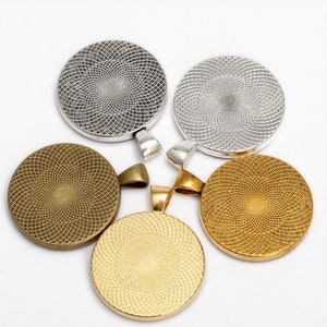 May include: Four round metal pendant bases with a decorative pattern. Two are silver and two are gold.