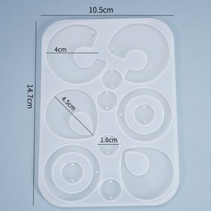 Puede incluir: Un molde de silicona blanco para hacer pendientes. El molde tiene 10 formas diferentes, incluyendo c&iacute;rculos, &oacute;valos y l&aacute;grimas. El molde mide 10,5 cm por 14,7 cm.