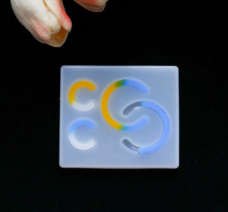 May include: A clear silicone mold with three different shapes of curved lines. The lines are in shades of blue, yellow, and white.
