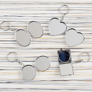 May include: Set of five silver keychain mirrors. Two are round, two are heart-shaped, and one is square.