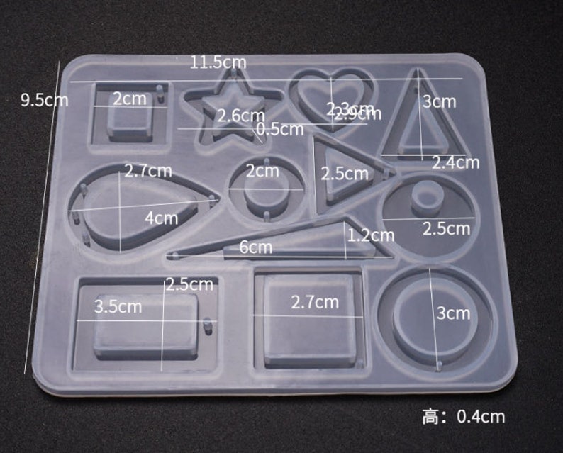 May include: A clear silicone mold with 12 different shapes for crafting. The shapes include a star, heart, circle, square, teardrop, and more. The mold measures 11.5 inches by 9.5 inches and is 0.4 inches high.