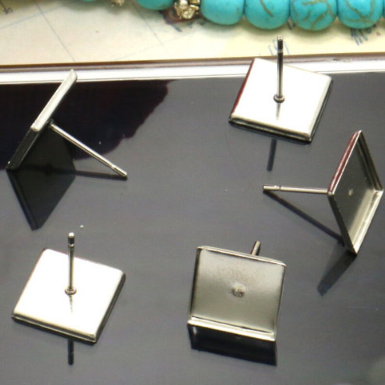 Pu&ograve; includere: Cinque montature per orecchini quadrate in argento con perni. Le montature sono vuote e pronte per essere riempite con resina o altri materiali.