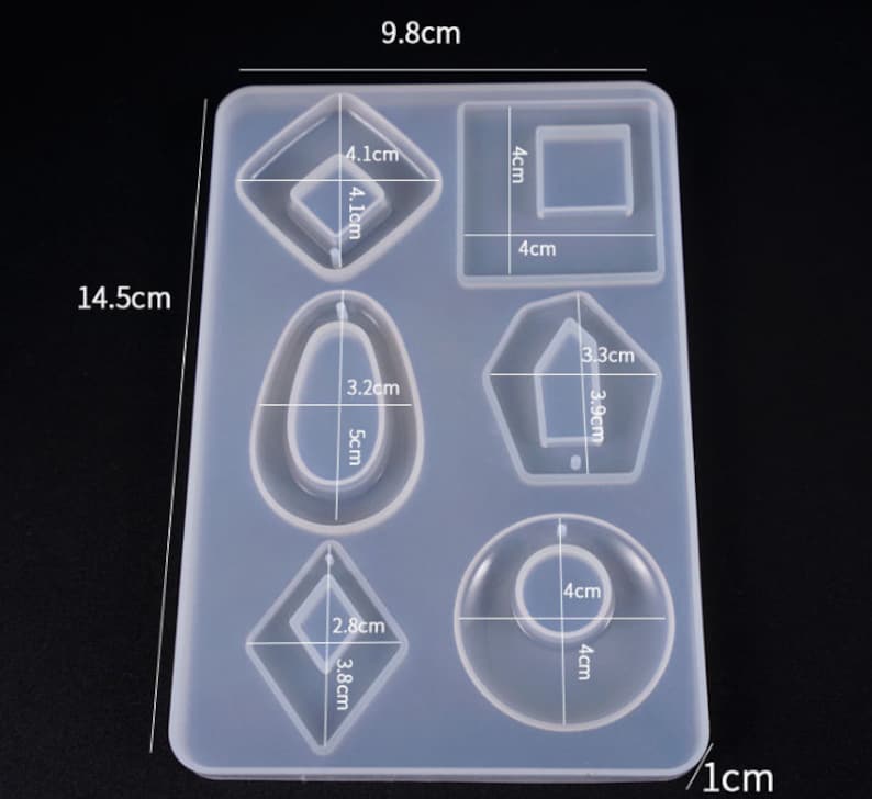 May include: Clear silicone mold with seven different shapes for resin casting. The mold measures 9.8 cm by 14.5 cm and includes shapes like a rectangle, oval, diamond, and a pentagon.