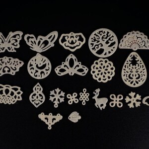 May include: A set of 18 white, decorative, laser-cut, metal shapes. The shapes include butterflies, snowflakes, a deer, a tree, a flower, and more.