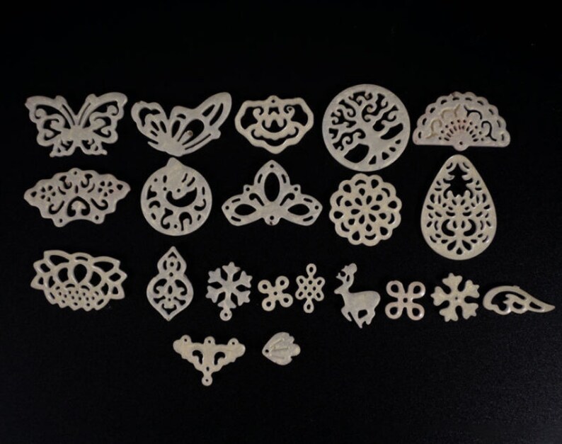 May include: A set of 18 white, decorative, laser-cut, metal shapes. The shapes include butterflies, snowflakes, a deer, a tree, a flower, and more.