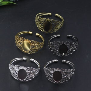May include: Set of five gold, silver, and black filigree metal bracelets with oval-shaped glass cabochon settings.