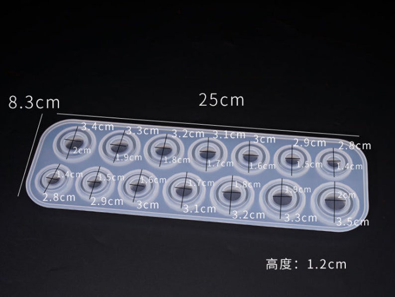Puede incluir: Un molde de silicona transparente y rectangular con 15 cavidades circulares de diferentes tama&ntilde;os. El molde mide 25 cm de largo, 8,3 cm de ancho y 1,2 cm de grosor. Cada cavidad est&aacute; etiquetada con su di&aacute;metro en cm.
