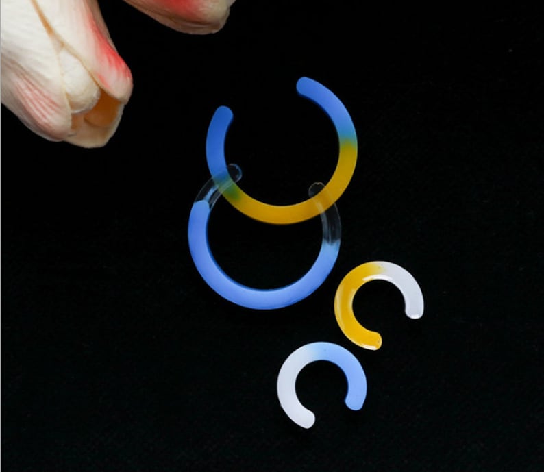 May include: Three hoop earrings in different sizes. The largest hoop is blue and yellow, the medium hoop is blue, and the smallest hoop is yellow.