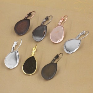 Puede incluir: Seis pares de bases para pendientes en forma de lágrima con acabados en plata, oro y bronce. Las bases para pendientes están listas para ser personalizadas con tus adornos favoritos.