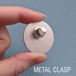 The back of an enamel pin with a metal locking clasp.