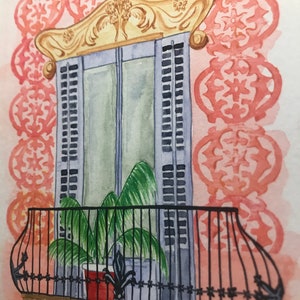 May include: A watercolor painting of a window with a balcony. The window is decorated with ornate gold trim and has blue shutters. A potted plant sits on the balcony, which has a black wrought iron railing.