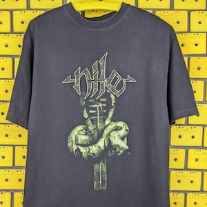 May include: Black t-shirt with a green and white graphic of a snake wrapped around a cross with the word "NILE" above it.
