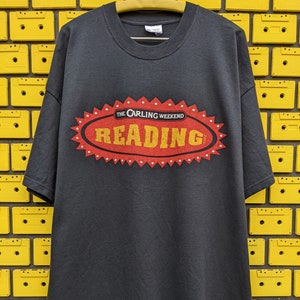 May include: Black t-shirt with a red and white logo that says "The Carling Weekend Reading 2002".