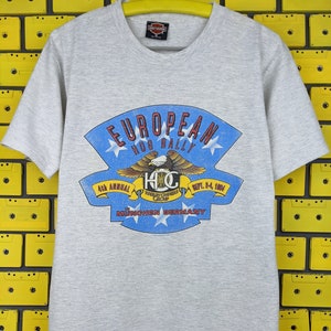 May include: Gray t-shirt with a Harley Davidson logo and a graphic of an eagle with the text "European Hog Rally 4th Annual Sept. 2-4, 1984 Munchen Germany".