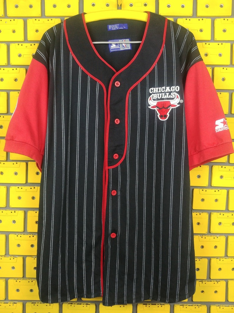 May include: Black and red striped baseball jersey with the Chicago Bulls logo and Starter branding. The jersey has red piping and a button-up front.