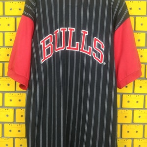 May include: Black and red baseball jersey with white pinstripes and the word "BULLS" in red on the back.
