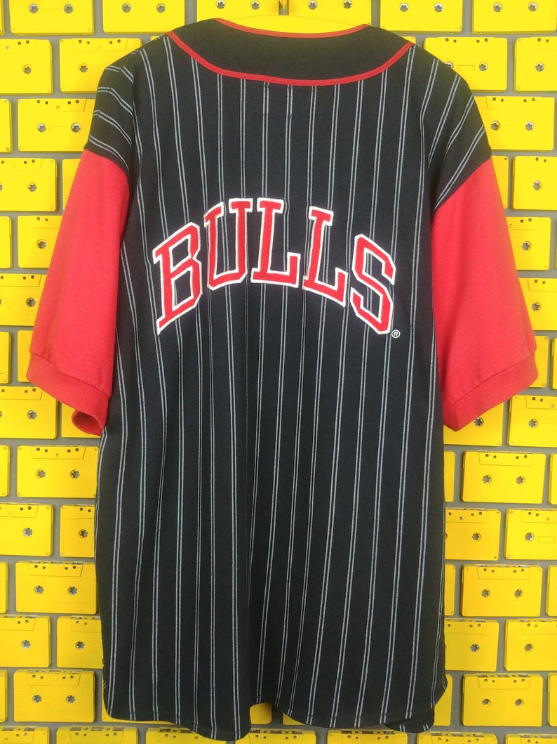 May include: Black and red baseball jersey with white pinstripes and the word "BULLS" in red on the back.