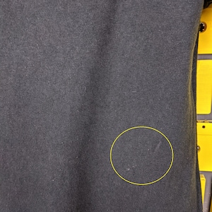 May include: Black fabric with a small white mark. The fabric has a slight texture.