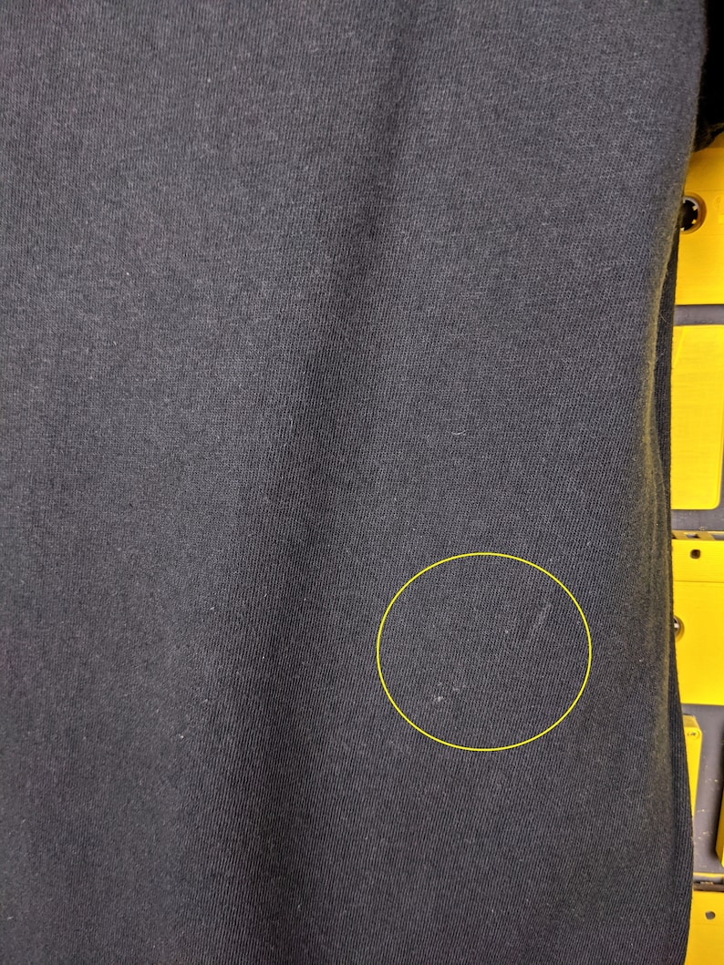 May include: Black fabric with a small white mark. The fabric has a slight texture.